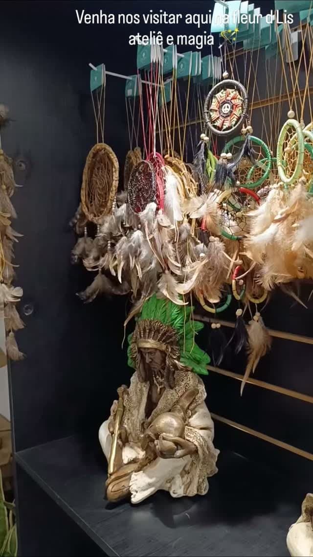 Filtros dos sonhos com penas pendurados num expositor, com uma imagem indígena dourada embaixo